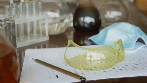 In the chemistry class on the table is exam test, pencil, goggles and mask fo Stock Footage 113348105