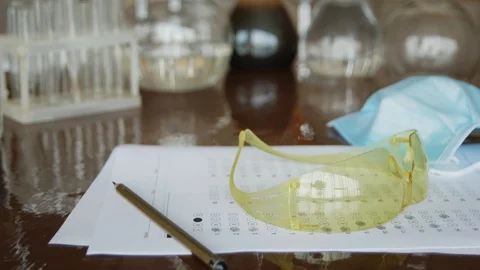 In the chemistry class on the table is exam test, pencil, goggles and mask fo Stock Footage 113348109