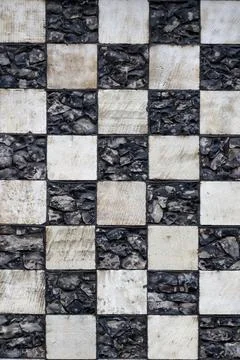 Chequerboard stone pattern on medieval church for use as a background texture Фото