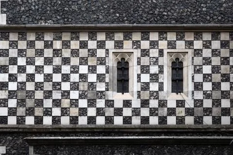 Chequerboard stone pattern on medieval church wall with small windows for u.. Stock Photos