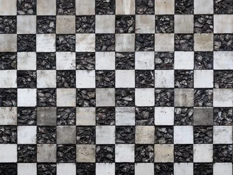 Chequerboard stone pattern on medieval church for use as a background texture Stock Photos