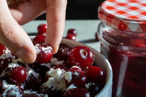 Cherries and a jar of jam on background and fresh fruits on the table, closeup Stock Photos