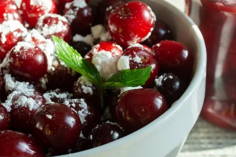 Cherries and a jar of jam on background and fresh fruits on the table, closeup Stock Photos