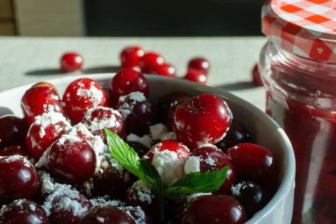 Cherries and a jar of jam on background and fresh fruits on the table, closeup Stock Photos