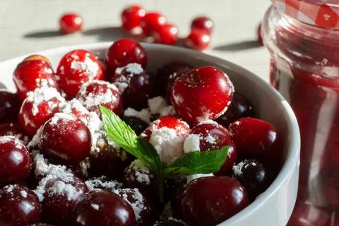 Cherries and a jar of jam on background and fresh fruits on the table, closeup Stock Photos