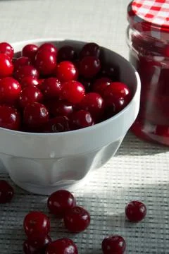 Cherries and a jar of jam on background and fresh fruits on the table, closeup Stock Photos