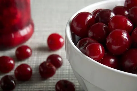Cherries and a jar of jam on background and fresh fruits on the table, closeup Stock Photos