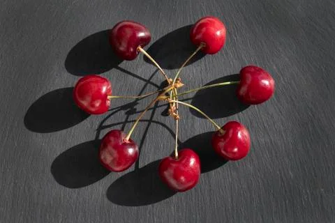 Cherries flat design background. Cherry with stalks on black plate background Stock Photos