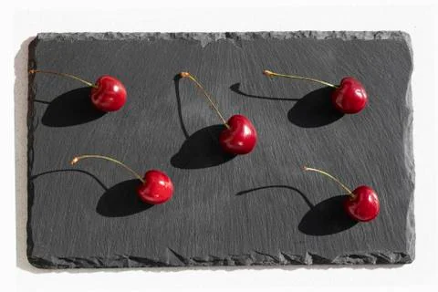Cherries flat design background. Cherry with stalks on black plate background Stock Photos