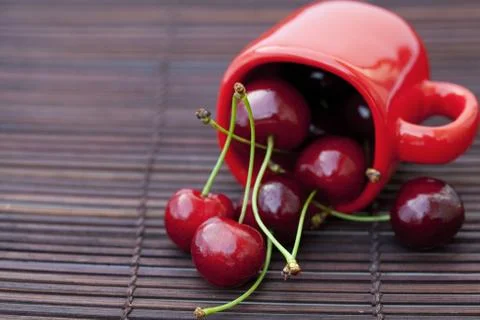 Cherry  and cup  on bamboo mat Stock Photos