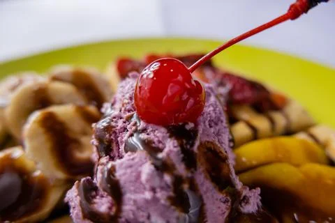 Cherry and ice cream on top of fruit decorated with chocolate syrup Stock Photos