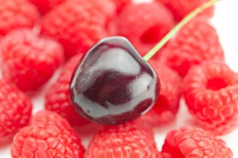 Cherry on a background of raspberry Stock Photos