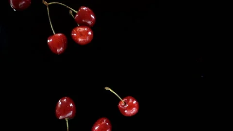 Cherry berries fall in slow motion on a wet black Stock Footage 133222569