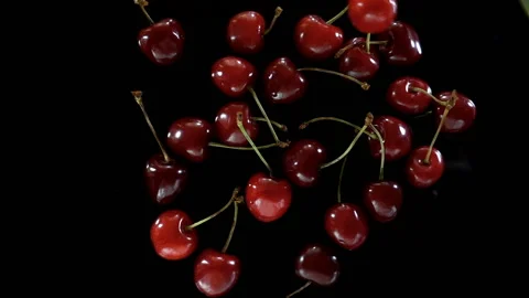 Cherry berries falling in slow motion on a black Stock Footage 134728707