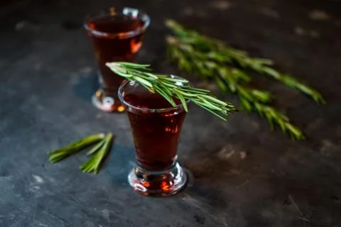 Cherry, berry tincture on a dark background, with a sprig of rosemary Stock Photos