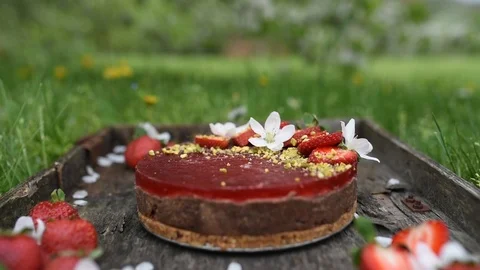 Cherry blossom falling in the background of Raw vegan cake with strawberries Video stock 88690526