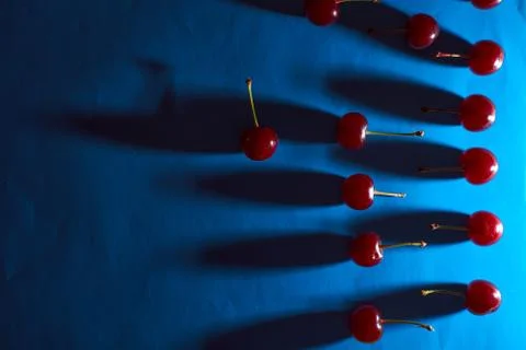 Cherry on blue background with shadows effect Stock-Fotos