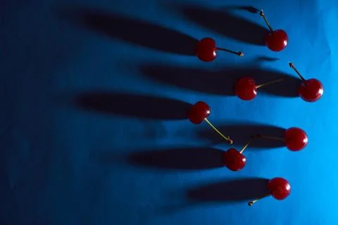 Cherry on blue background with shadows effect. Concept photo. With copy space Stock Photos