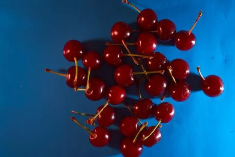 Cherry on blue background with shadows effect. Close-up. Stock Photos