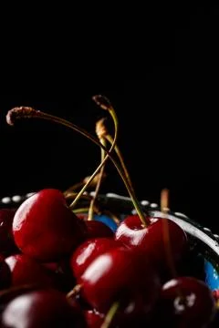 Cherry in a bowl close-up on a black background Фото