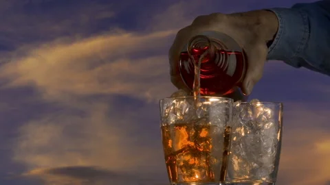 Cherry drink pours over ice against evening sky Stock Footage 139258073
