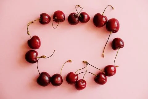 Cherry frame. Flat lay of cherries on a soft pink background. Stock Photos