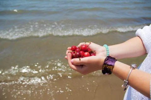 Cherry in hand on a sea background Stock Photos