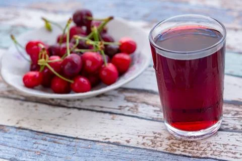 Cherry juice with cherries in plate on turquoise vintage table Stock Photos