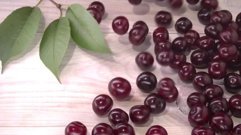 Cherry. Organic cherries are rolling on the white wooden table. Video stock 81827961