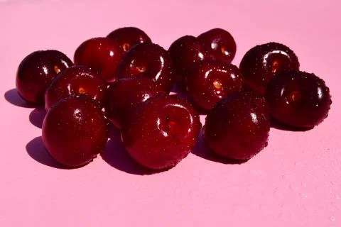 Cherry pattern with splashing water. Flat lay of cherries on a pink backgroun Stock Photos