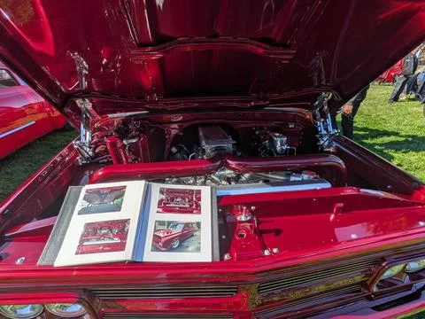 A cherry red custom car with hood up reveals a polished silver engine 库存照片