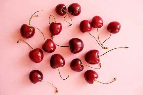 Cherry scattering. Flat lay of cherries on a soft pink background. Foto stock