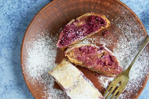 Cherry strudel pastry on rustic plate on the blue abstract backdrop flatlay Stock Photos