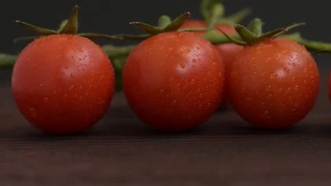 Cherry tomato branches on wooden surface, water drops on vegetables, dark backgr Stock Footage 267602968