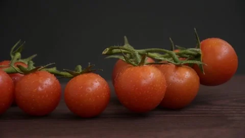 Cherry tomato branches on wooden surface, water drops on vegetables, dark backgr Stock Footage 267603422