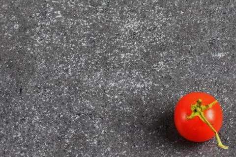 Cherry tomato on a grey abstract stone background. Space for text. Stock Photos