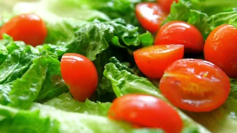 Cherry tomato halves falling onto fresh green lettuce leaves 스톡 동영상 332280896