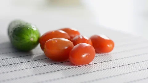 Cherry tomatoes and green cucumber on a white table Stock Footage 124190551
