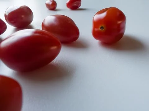 Cherry tomatoes are lying on a white table, space for a text Stock Photos