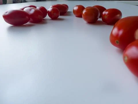 Cherry tomatoes are lying on a white table, space for a text 스톡 사진