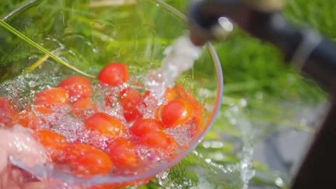 Cherry tomatoes being rinsed under a garden tap with splashing water in a b.. Stock Footage 286814967