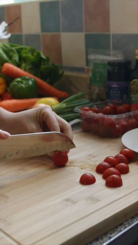 Cherry tomatoes being sliced in half on a bamboo cutting board. Stock Footage 304005957