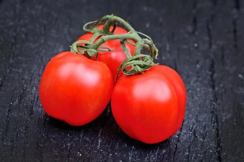Cherry tomatoes on black old table Stock Photos