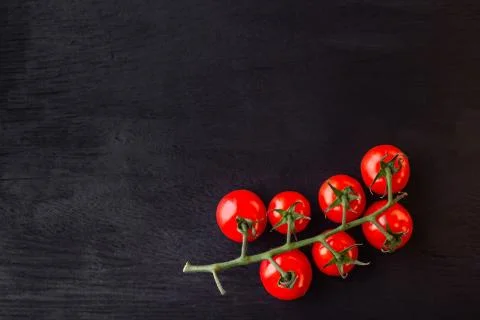 Cherry tomatoes on a black wooden table. Copy space. Foto stock