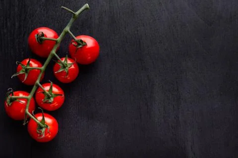 Cherry tomatoes on a black wooden table. Copy space. Stock Photos
