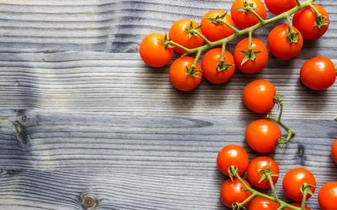 Cherry tomatoes on a branch on a black rustic wooden table Stock Photos
