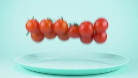 Cherry tomatoes on a branch falling on a blue dish. blue background Stock Footage 122013560