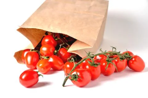 Cherry tomatoes on a branch, paper bag, light background Stock Photos