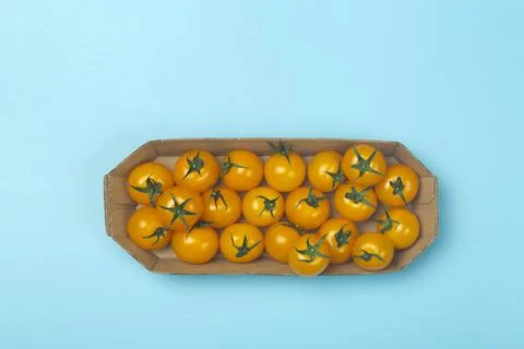 Cherry tomatoes on a colored blue background. Cherry tomatoes in a package fr Stock Photos