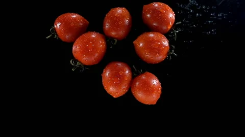 Cherry tomatoes in drops of water on a black in slow motion Stock Footage 134732879